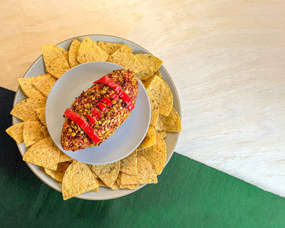 Football-shaped cheese ball on a platter with tortilla chips
