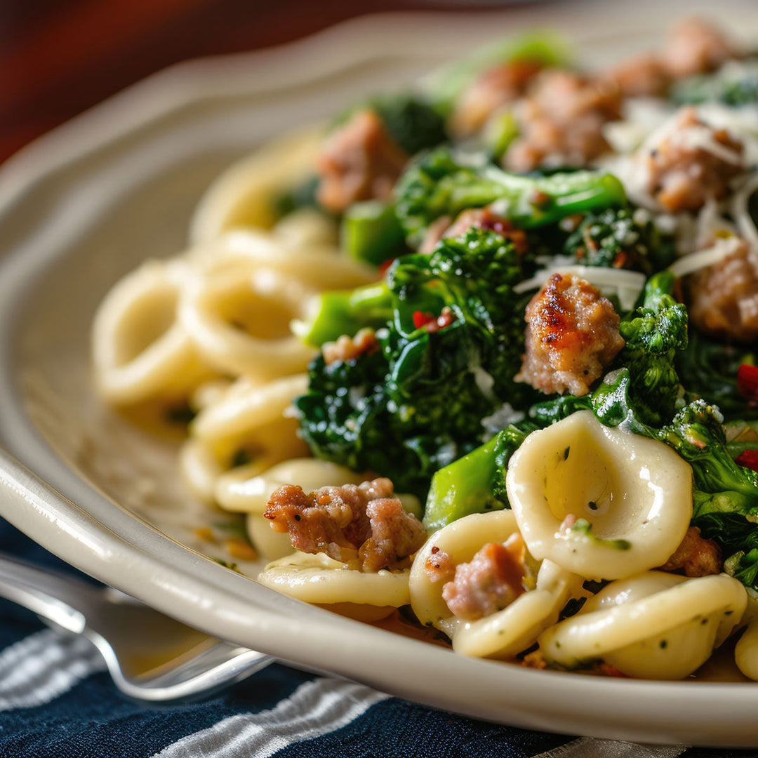 Orecchiette pasta with broccoli rabe and crumbled sausage in a white bowl