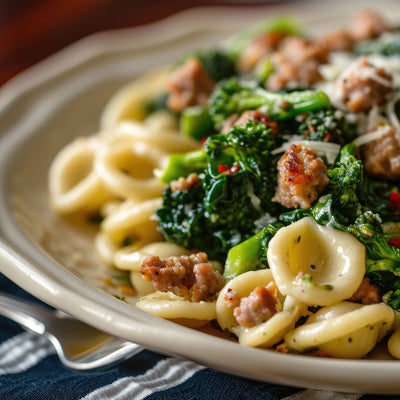 Orecchiette pasta with broccoli rabe and crumbled sausage in a white bowl
