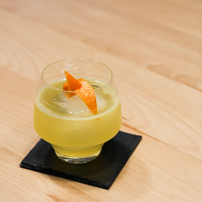 Bee's Knees Cocktail in a glass with an orange twist