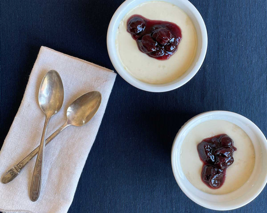 Two ramekins of Black Orchid Tea panna cotta topped with Basque cherry jam