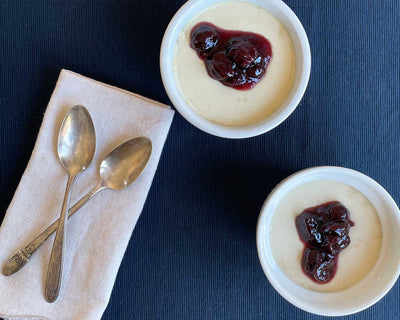Two ramekins of Black Orchid Tea panna cotta topped with Basque cherry jam