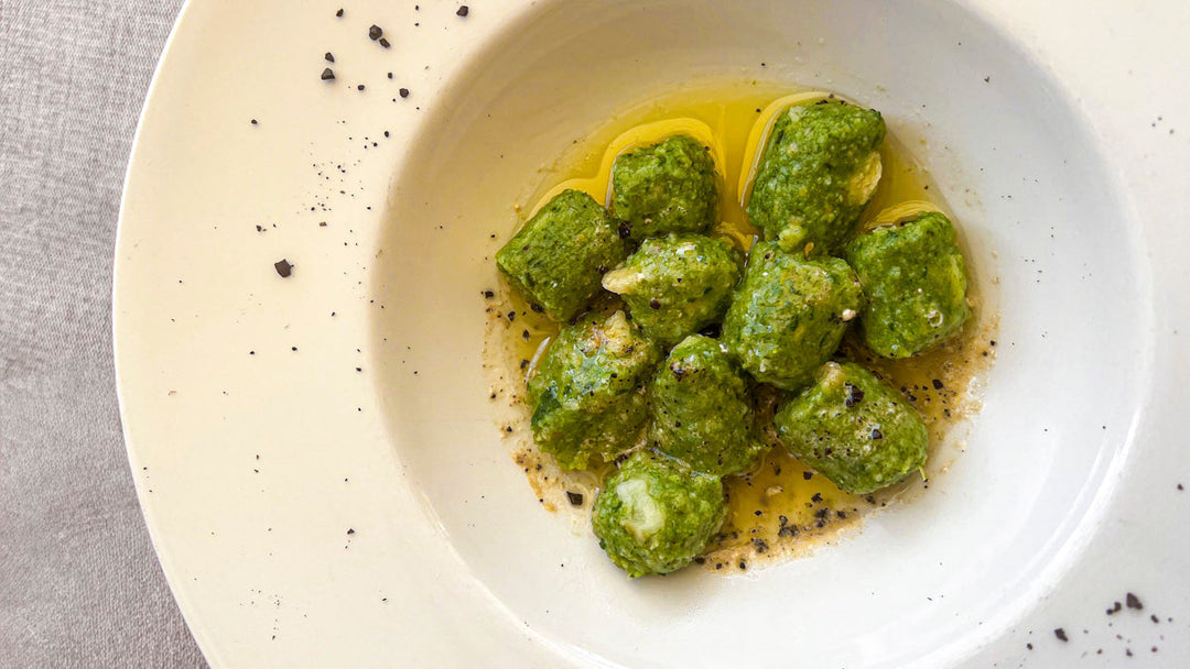 Green spinach and crucolo gnudi dumplings in a white bowl