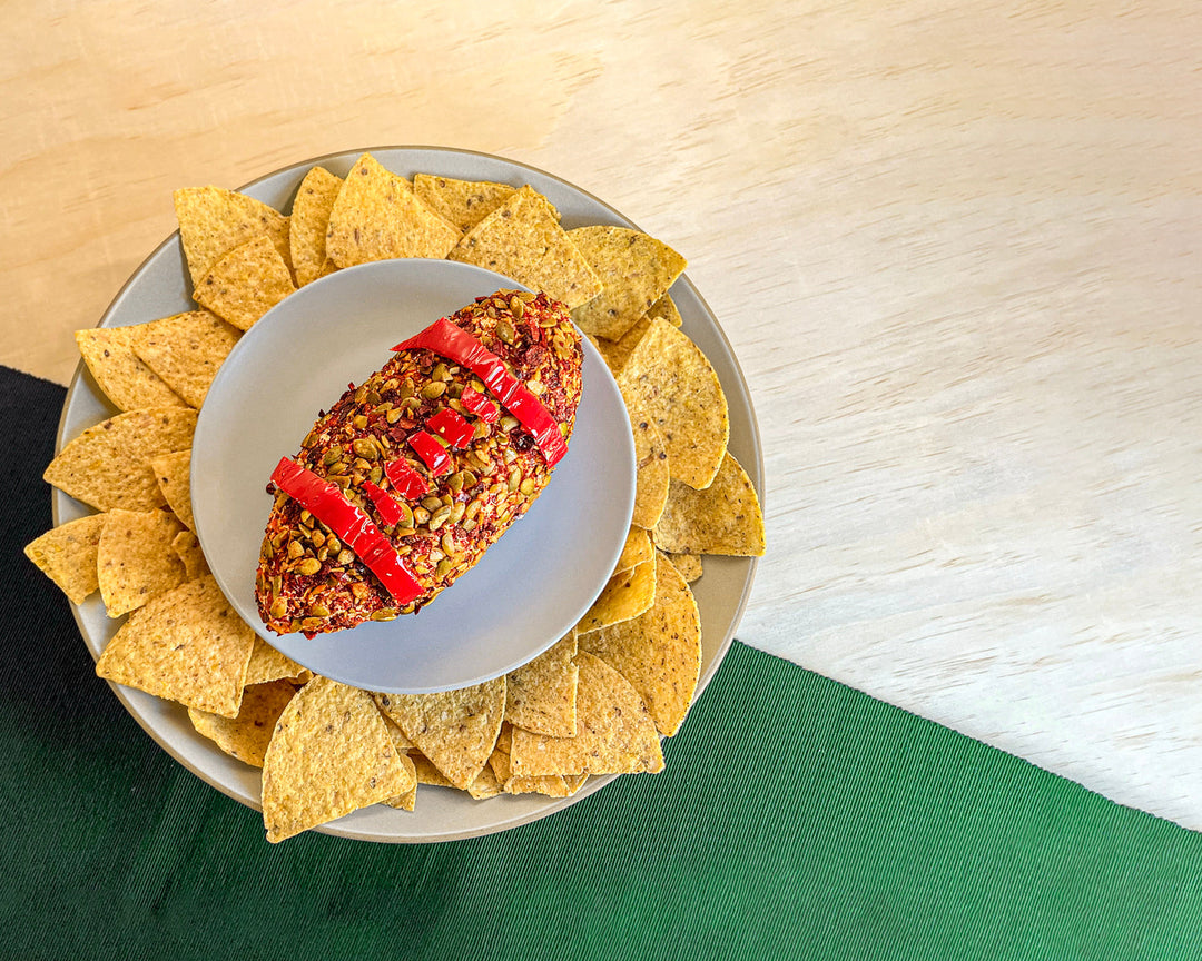 Football-shaped cheese ball on a platter with tortilla chips