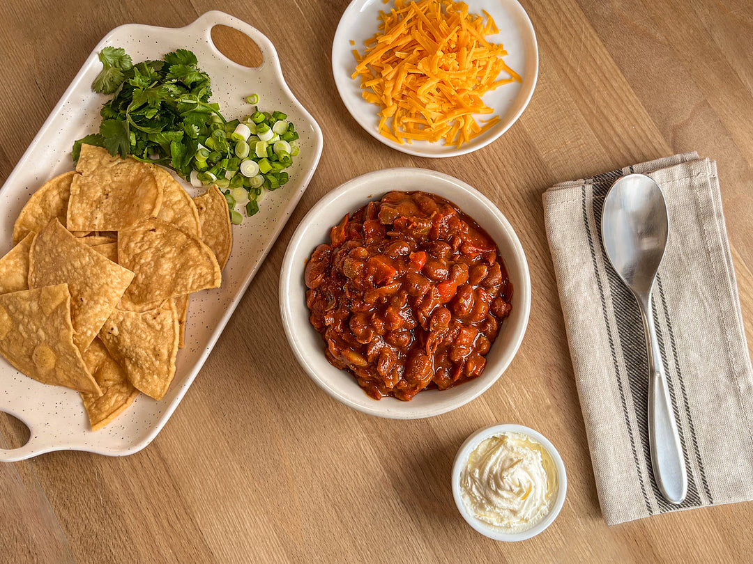 A bowl of Smoky Vegetarian Chili with fixings on the side