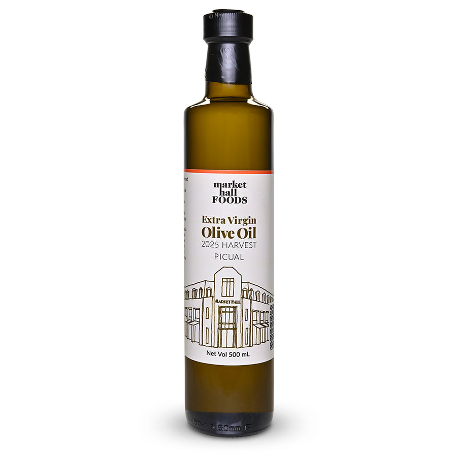 A 500 ml glass bottle of Market Hall Foods Extra Virgin Olive Oil from the 2025 Harvest, featuring a white label with black text and a line drawing of the Picual building, set against a plain white background.
