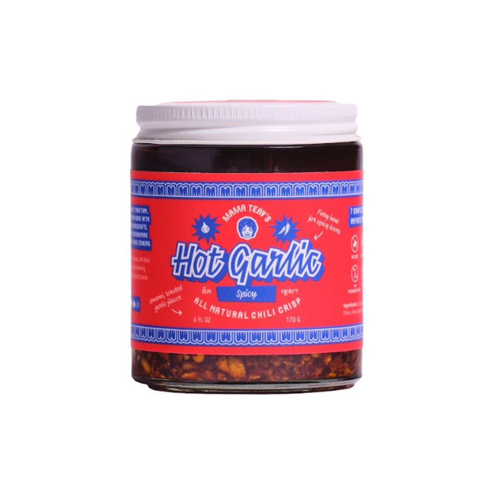 A jar of Mama Teavs Hot Garlic Spicy, featuring a bright red label with blue text and a white lid, set against a plain white background.