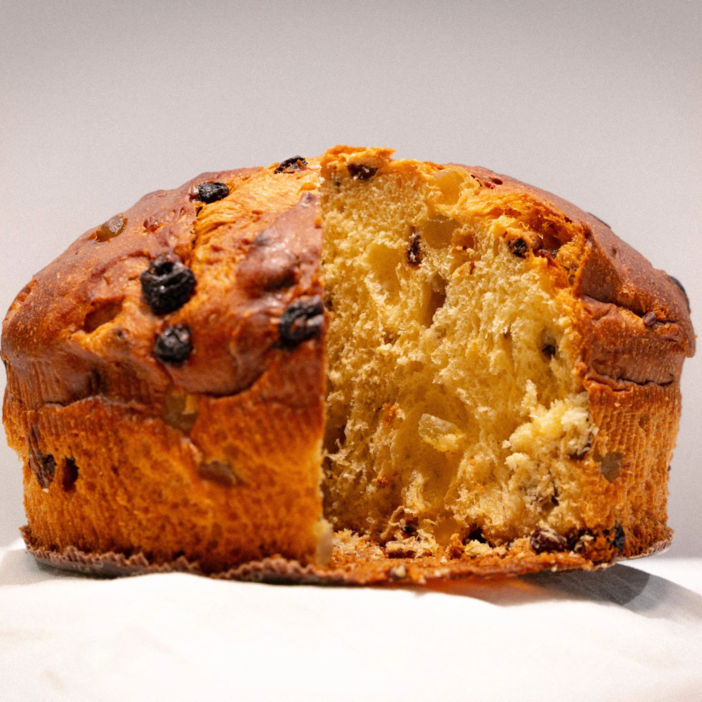 Citron panettone with a slice cut open on a white background