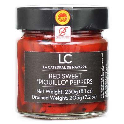 Jar of red sweet piquillo peppers with a black lid and label on a white background