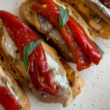 Sardines with piquillo peppers on a speckled plate